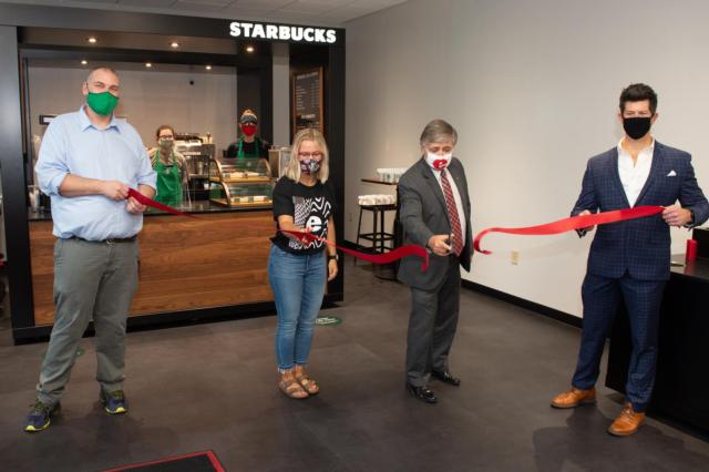 SIUE Dining Services Administrator Matt Turner (far left) and Director Dennis Wobbe (far right) hold the ceremonial ribbon while SIUE Student Government President Maddie Walters and Chancellor Randy Pembrook cut it, marking the official opening of the Starbucks Library Cart.