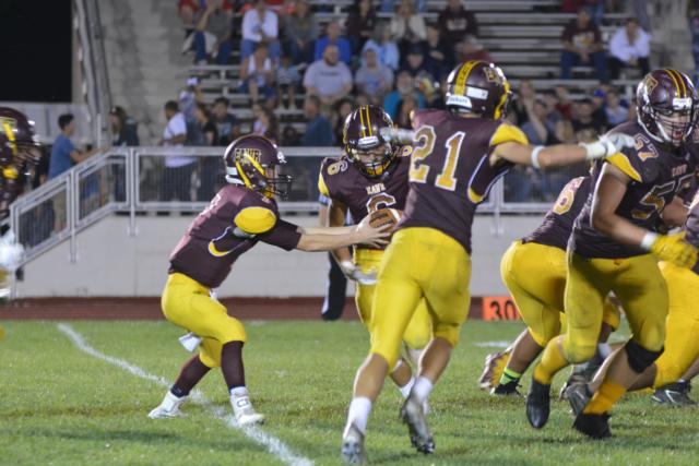 Oiler quarterback Justin Englar hands the ball off to No. 6 Zach Womack in Friday's game against Taylorville. (Photo by Dan Brannan)