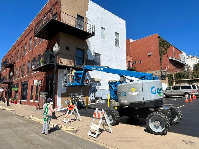 Robert Fishbone adjusts his machinery while James K. Schmidt's daughter Penny Schmidt directs him from the ground.