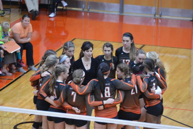 A tight-knit Edwardsville varsity volleyball team with their coach Jami Parker.