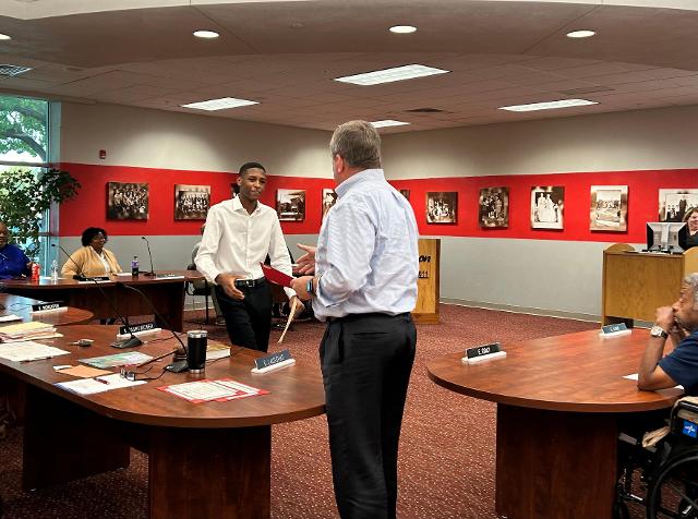 Keion Lacey, Jr. accepts a certificate from Board of Education President David Lauschke.