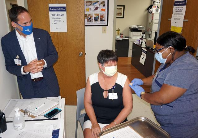 Brittany gives a COVID-19 vaccination shot to AMH gift shop coordinator Mary Norman under the watchful eye of Rich Liekweg, President and CEO of BJC.
