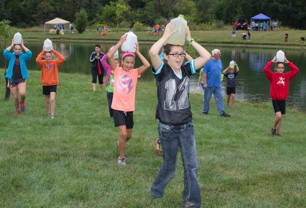 Fifth graders Bailey Tweedy, foreground, and Peyton Brown, of S t. Ambrose School, lead c lassmates as they carry water jugs on their heads to simulate what it would be like to c ollec t water in rural parts of G uatemala during L&C ’s 11th Annual W ater Festival. Tweedy is from Murphysboro, and Brown is from G odfrey. Photo by Louise Jett, L&C Media Specialist