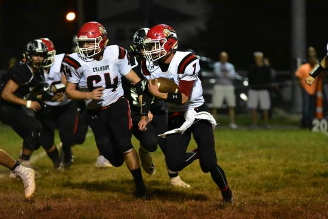 #64 Trenton Buchanan runs beside Quarterback Ty Bick, #7.